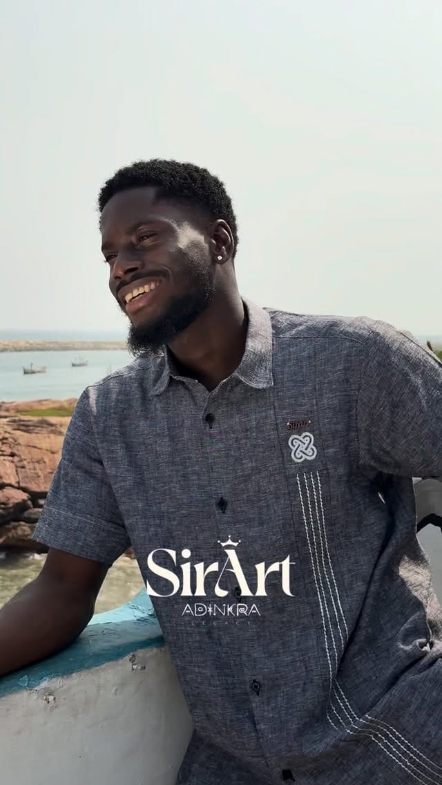 Man by the sea wearing a grey SirArt Adinkra shirt with tonal symbol embroidery