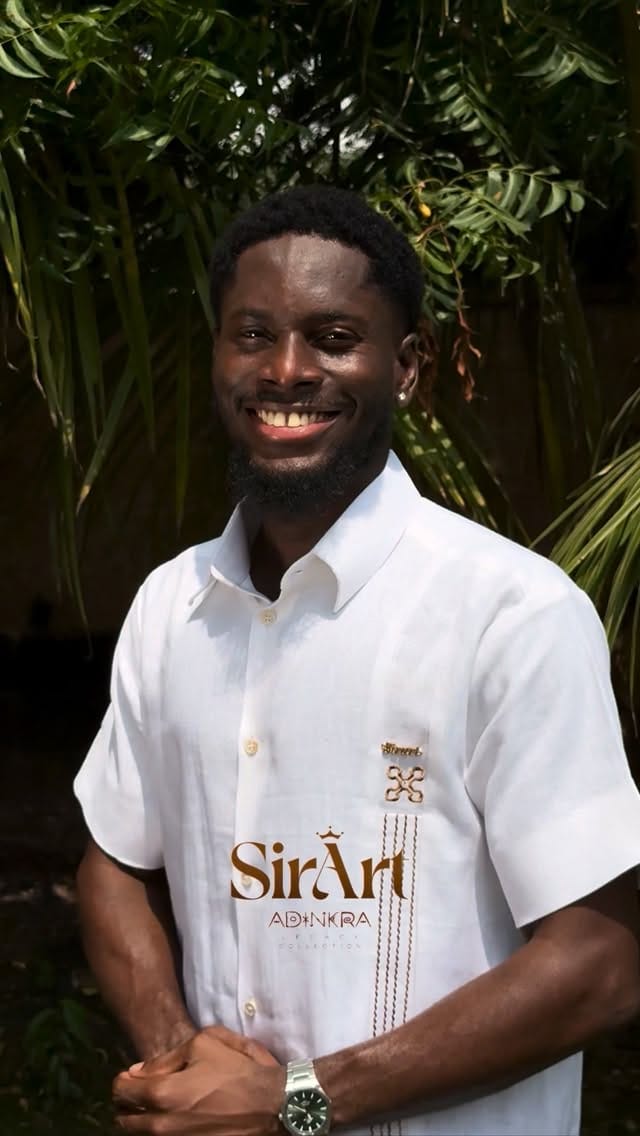 Smiling man outdoors in a white SirArt Adinkra shirt
