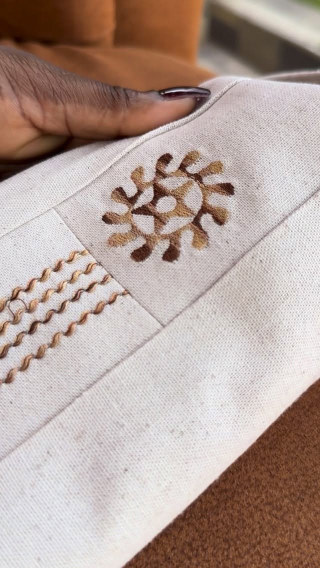 Natural linen embroidered with an Adinkra symbol and rows of brown stitching