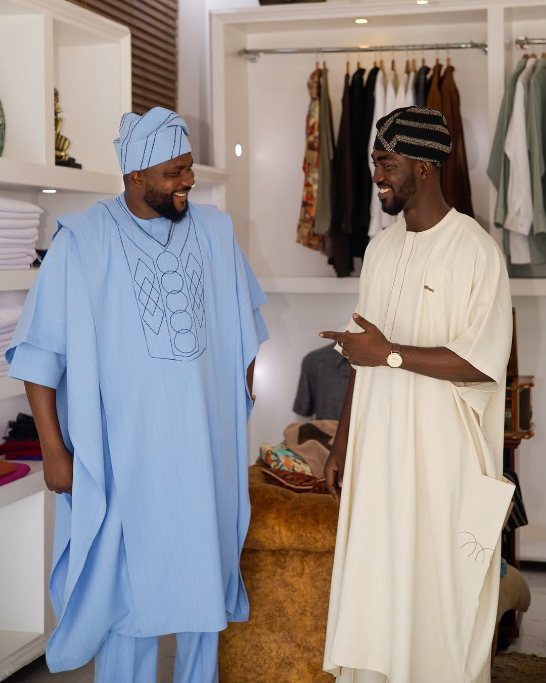 Two men in the SirArt showroom wearing embroidered agbada — one sky blue, one cream — from the Adinkra Legacy collection