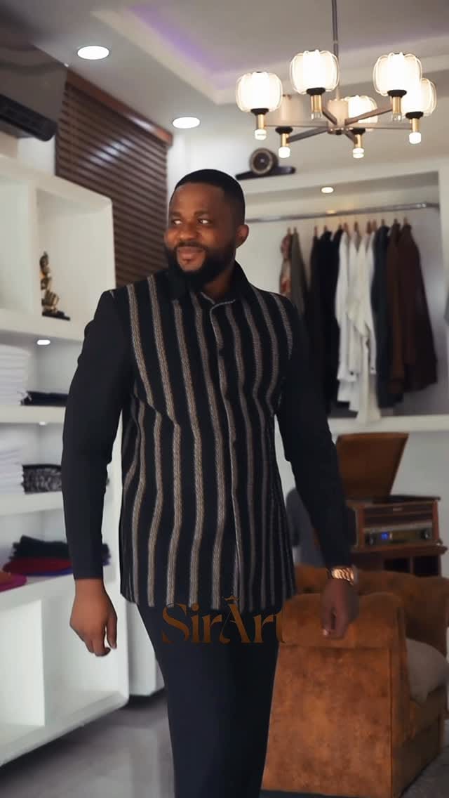 Man in a black-and-brown striped kaftan suit carrying a leather bag through the showroom